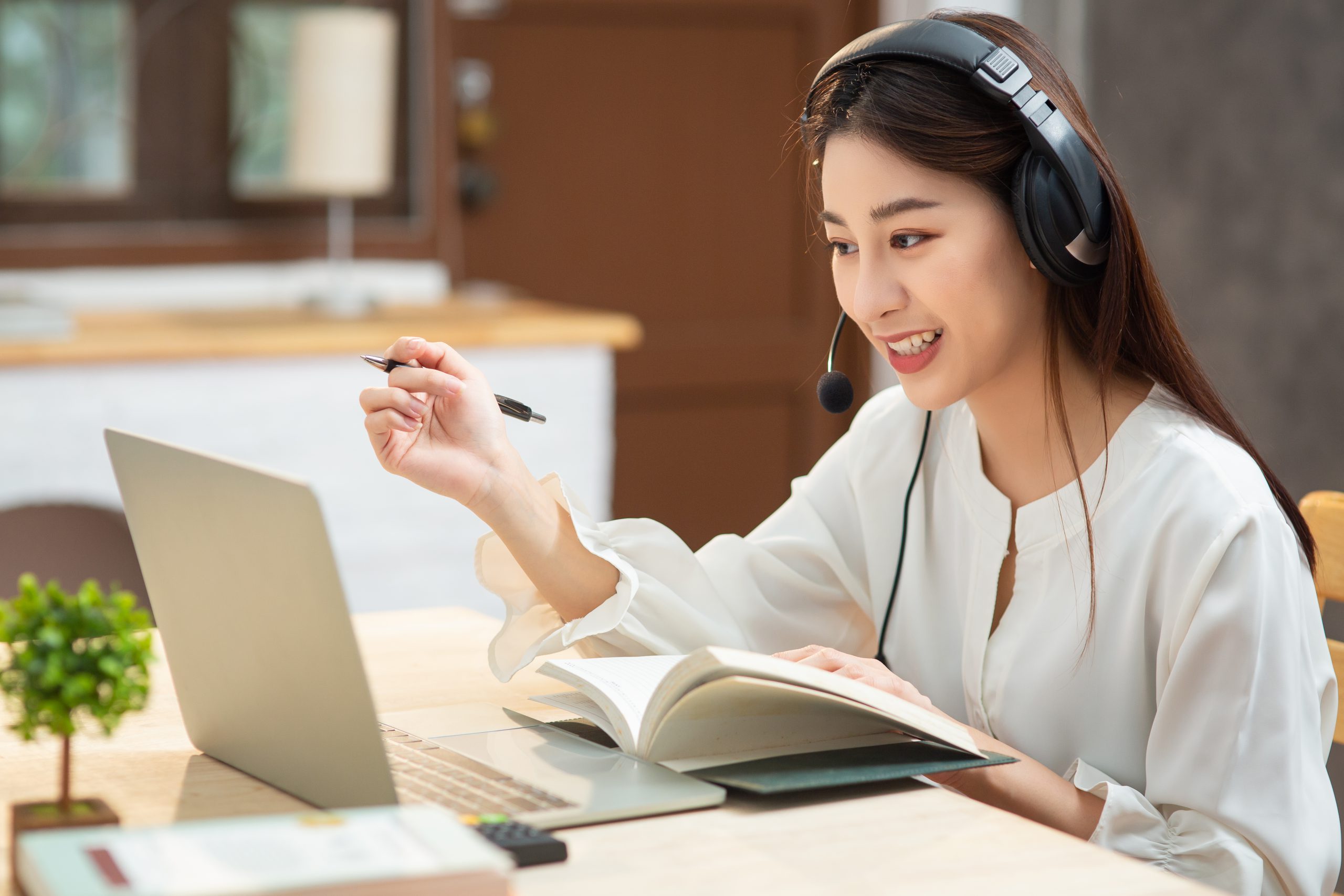 smiling-asian-young-female-using-headset-looking-laptop-screen-listen-learning-online-courses