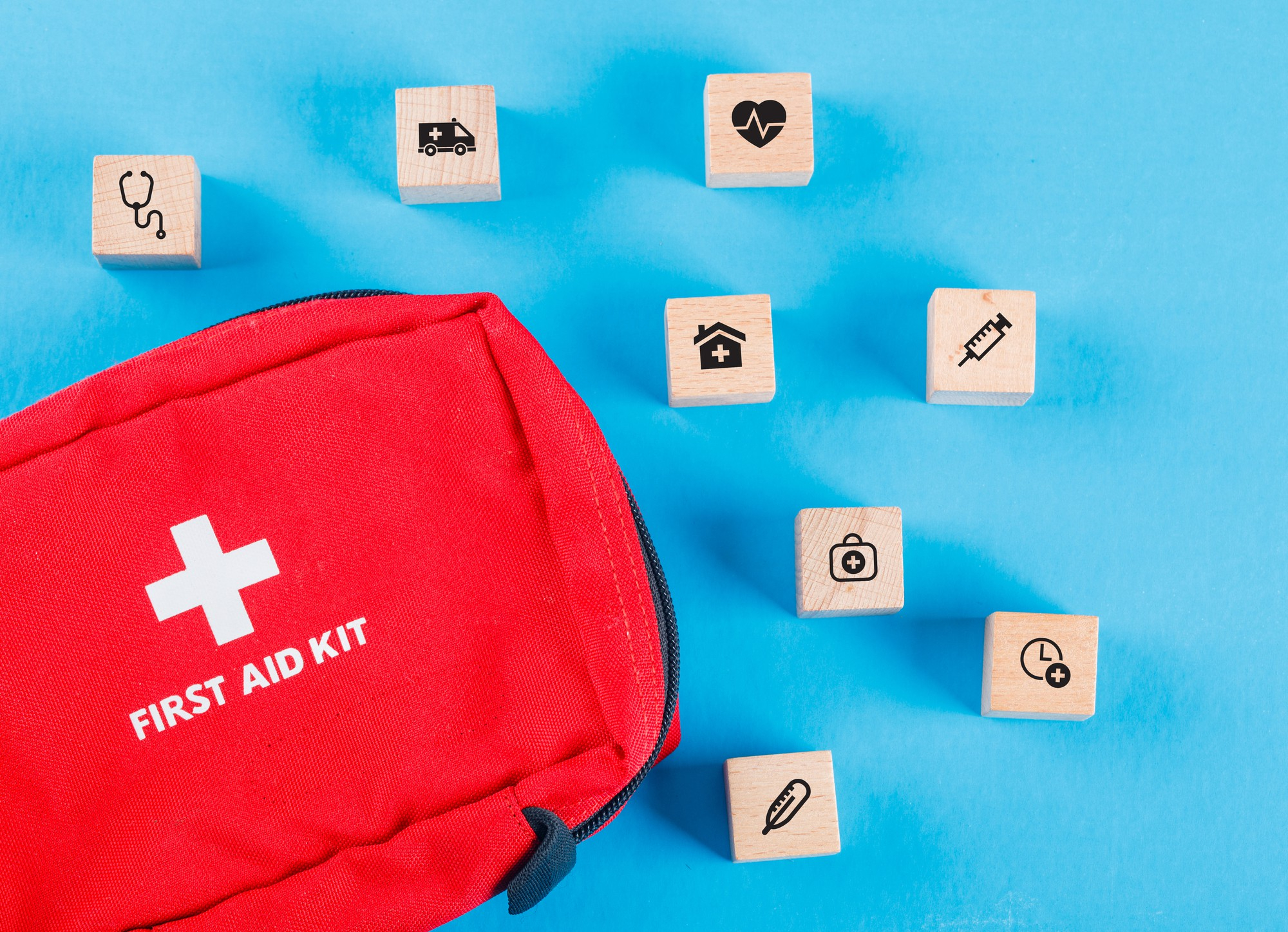 medical-concept-with-wooden-blocks-with-icons-first-aid-bag-blue-table-flat-lay (1)